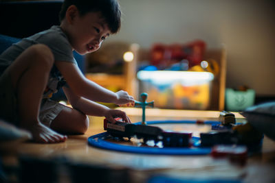 Side view of boy playing with miniature train at home