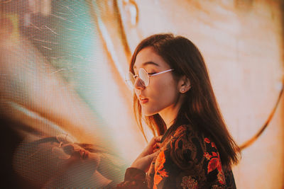 Portrait of young woman looking away against wall