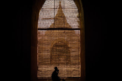 Silhouette man seen through glass window of building