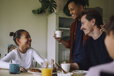 Happy gay couple with daughter having breakfast while sitting at dining table in home