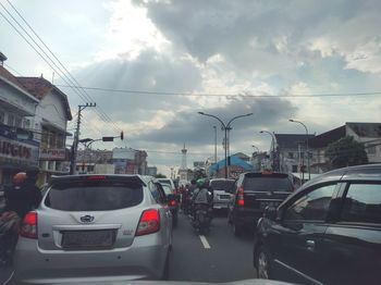 Cars on city street against sky