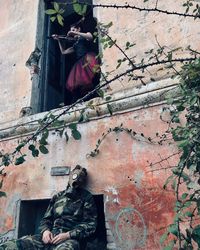 Low angle view of woman sitting against building