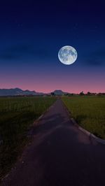 Scenic view of road amidst field against sky at night