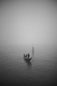 Silhouette people on boat in sea against sky
