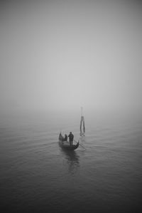 Silhouette people on boat in sea during foggy weather