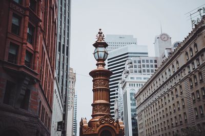 Low angle view of lamp post amidst buildings against sky