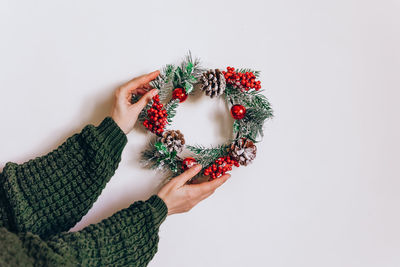 Wreath frame from pine and christmas decor in female hands on a light background. eelegant style