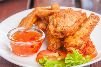 Close-up of roasted chicken with dip in plate