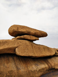 Low angle view of sculpture on rock against sky