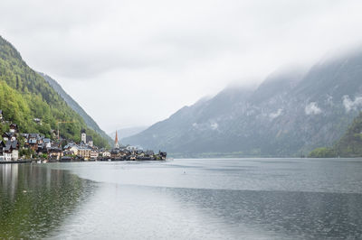 Scenic view of lake by mountains against cloudy sky