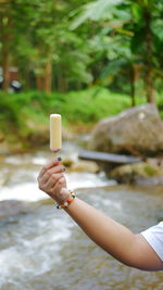 Midsection of woman holding ice cream cone against blurred background