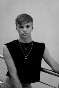 Portrait of young man standing against wall