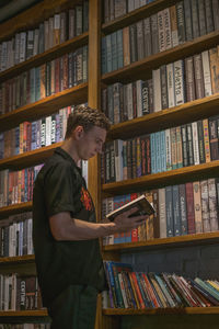 Young man reading book at library