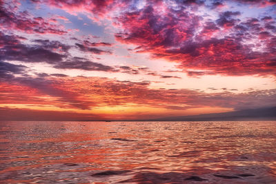 Scenic view of sea against dramatic sky during sunset