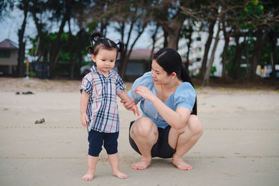 Mother carrying daughter on shoulders on beach vacation