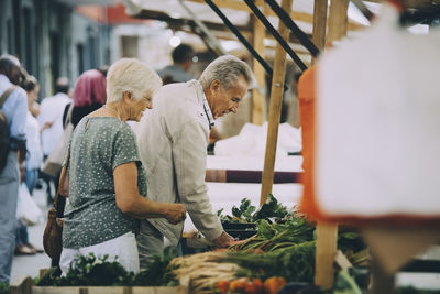 Senior male and females shopping for vegetables at market in city