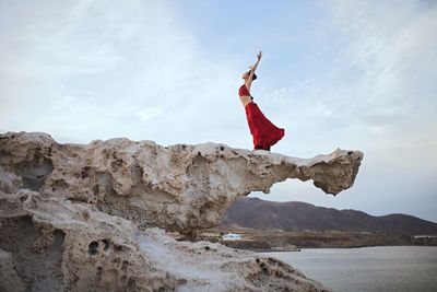 Woman in red dress on rock formation