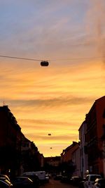 Cars on street against sky during sunset