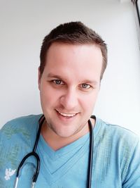 Close-up portrait of smiling mid adult man against white background