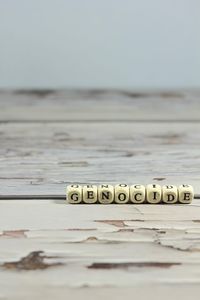 Close-up of text on table at beach against sky