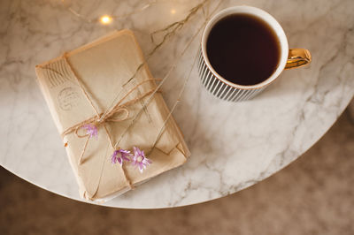 Cup of black tea with laced stack of old love paper letters on marble table close up. top view. 