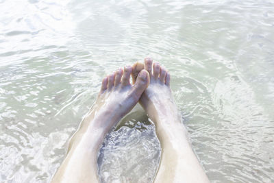 Low section of man relaxing in swimming pool