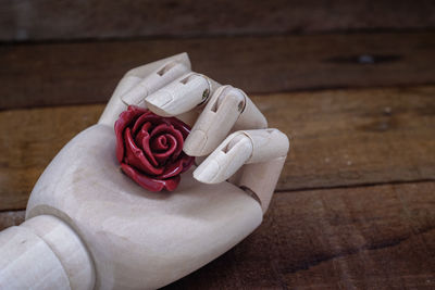 Close-up of hand figurine with flower on table