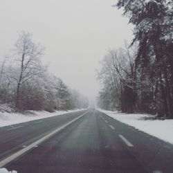 Road amidst trees against clear sky during winter