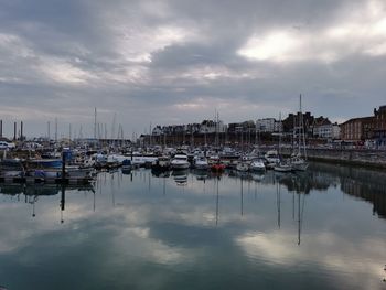 Sailboats moored in harbor against sky