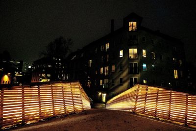 Illuminated street amidst buildings in city at night