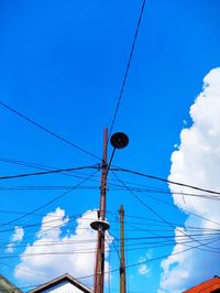 Low angle view of electricity pylon against blue sky