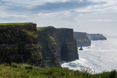 Scenic view of cliff by sea against sky