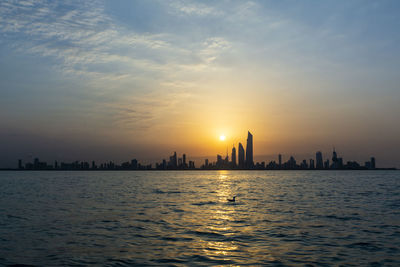 Scenic view of sea and buildings against sky during sunset