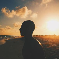 Silhouette of man at beach against sky during sunset