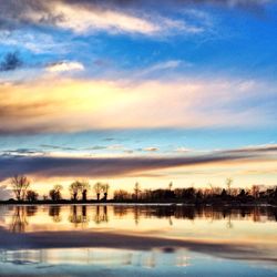 Reflection of trees in lake at sunset