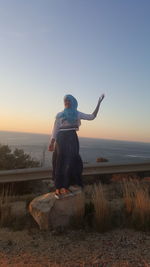 Girl standing on rock against sea