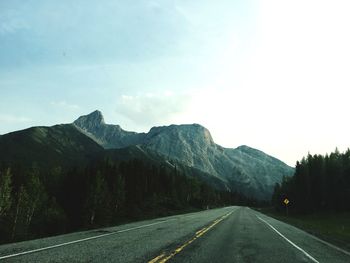 Empty road by mountains against sky