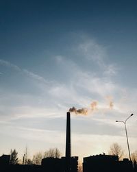 Low angle view of smoke emitting from chimney against sky