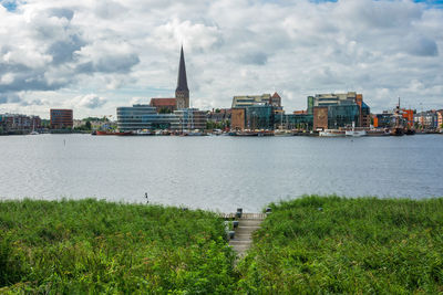 River with city in background against cloudy sky