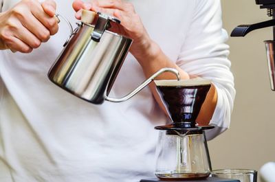 Midsection of man pouring coffee cup.