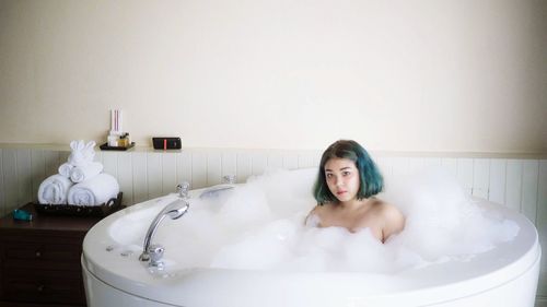 Portrait of woman sitting in bathtub at bathroom