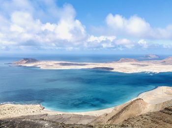 Scenic view of island beach against cloudy sky