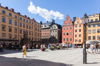 Crowd in town square by buildings against sky