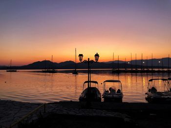 Silhouette sailboats moored in lake against sky during sunset