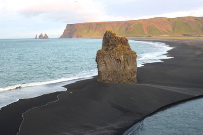 Scenic view of rocks on shore against sky