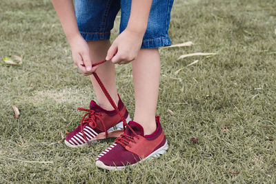 Low section of child tying shoelace of lawn