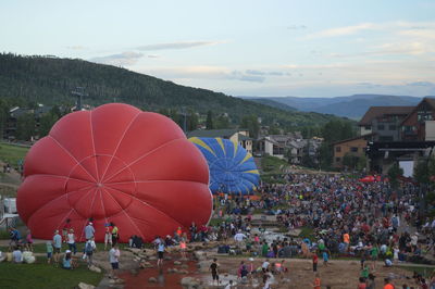 Crowd by hot air balloon on field in town