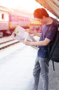 Man reading map while standing at railroad station platform