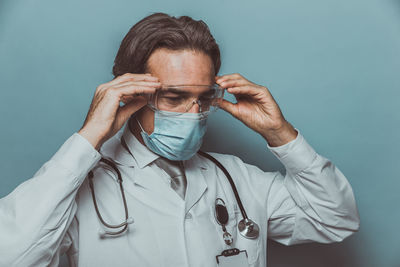Close-up of doctor wearing mask against colored background