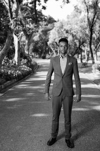 Portrait of young man standing against trees